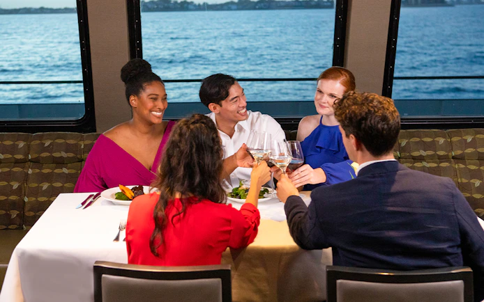 Group toasting at a table on a New York dinner cruise with ocean view.