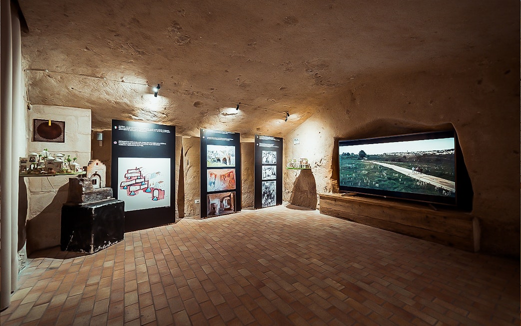 Exhibit room in Sassi of Matera tour with informational panels and video display.