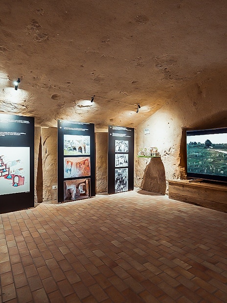Exhibit room in Sassi of Matera tour with informational panels and video display.