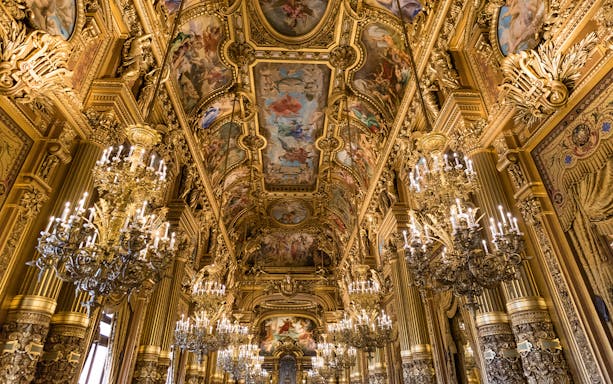Grand Foyer of Palais Garnier Opera with ornate chandeliers and detailed ceiling frescoes.
