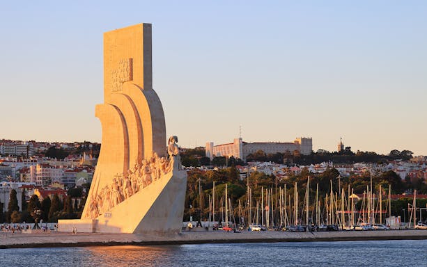 Padrão dos Descobrimentos monument in Lisbon at sunset with cityscape in background.