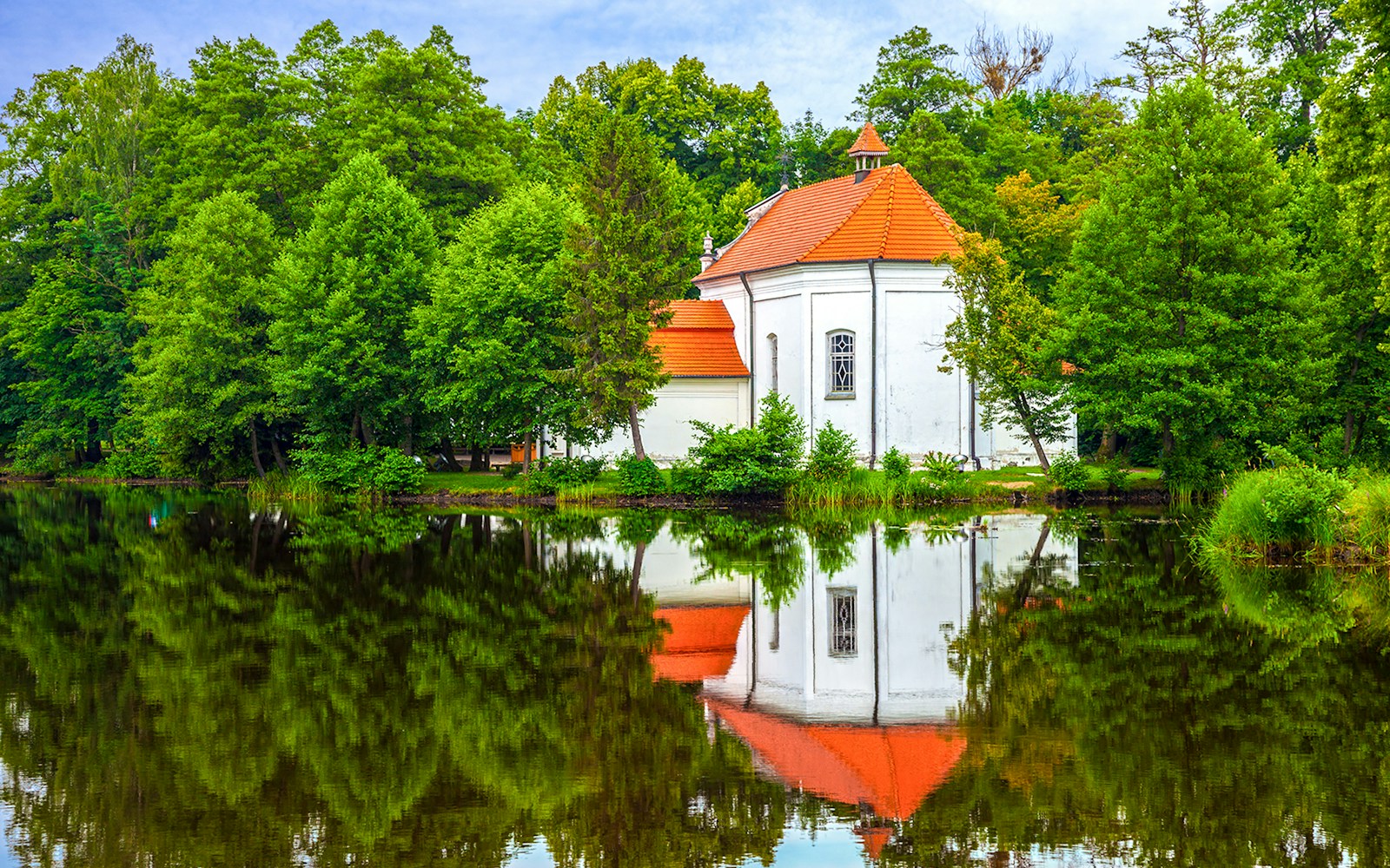 Church on the water surrounded by trees in Zwierzyniec, Poland.