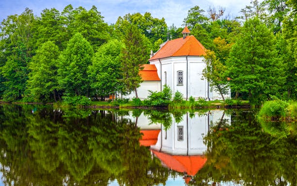 Church on the water surrounded by trees in Zwierzyniec, Poland.
