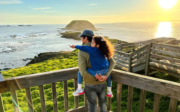 Visitor walking on Nobbies boardwalk overlooking coastal scenery, Phillip Island, Australia.