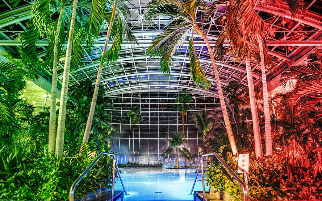 Indoor pool at the palm zone, Therme Bucharest, illuminated at night.