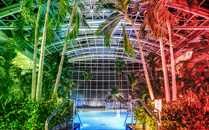Indoor pool at the palm zone, Therme Bucharest, illuminated at night.