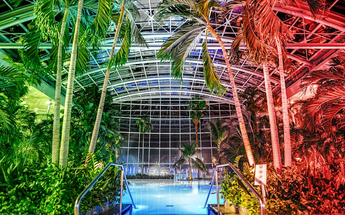 Indoor pool at the palm zone, Therme Bucharest, illuminated at night.