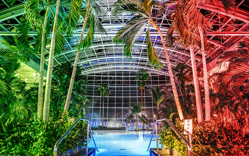 Indoor pool at the palm zone, Therme Bucharest, illuminated at night.