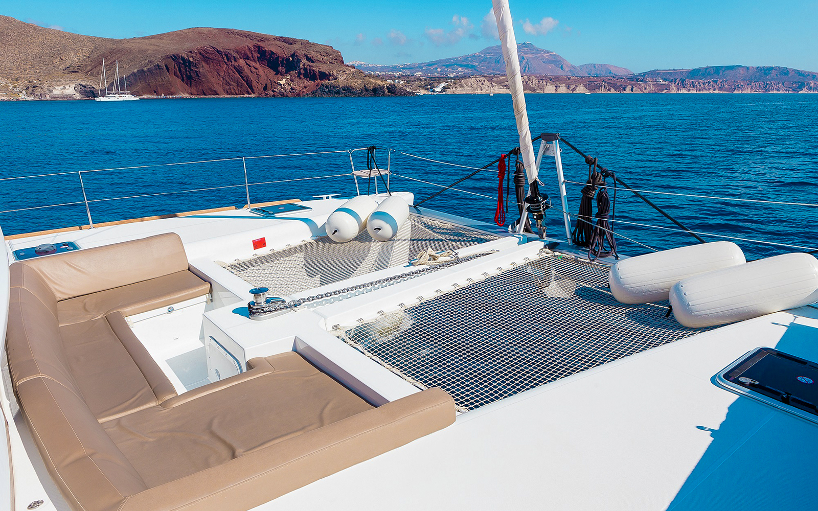 Santorini catamaran deck with sea and island views.