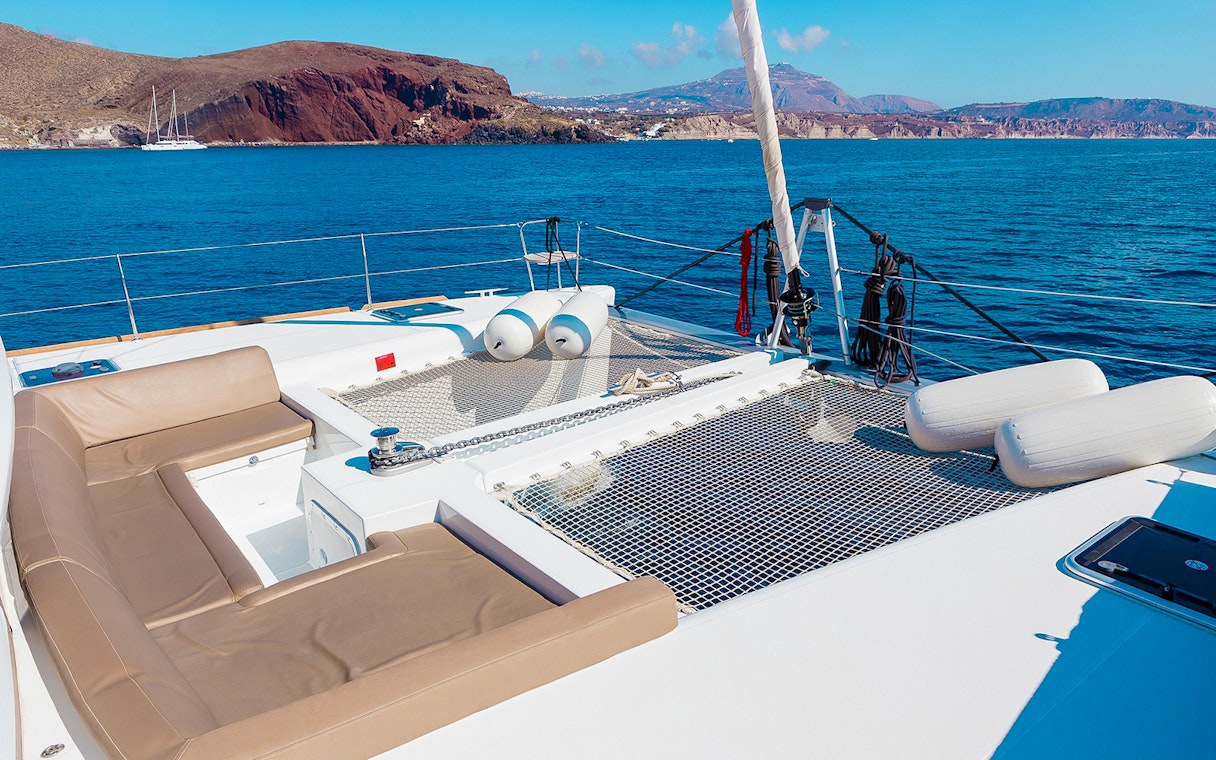 Santorini catamaran deck with sea and island views.