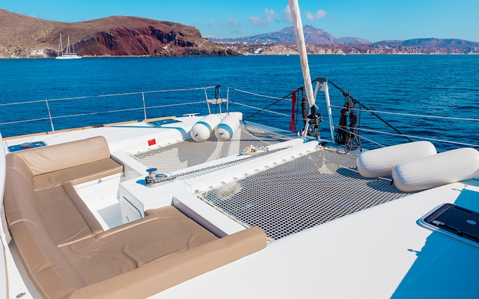 Santorini catamaran deck with sea and island views.