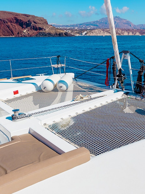 Santorini catamaran deck with sea and island views.