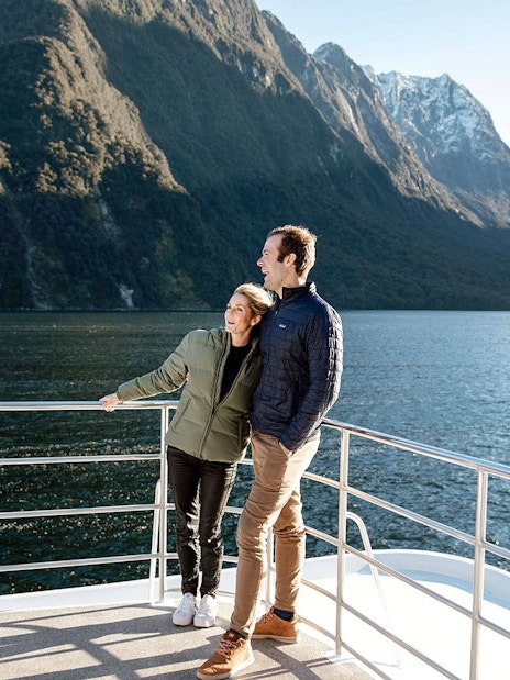 Couple on a boat enjoying Milford Sound's scenic mountain views.
