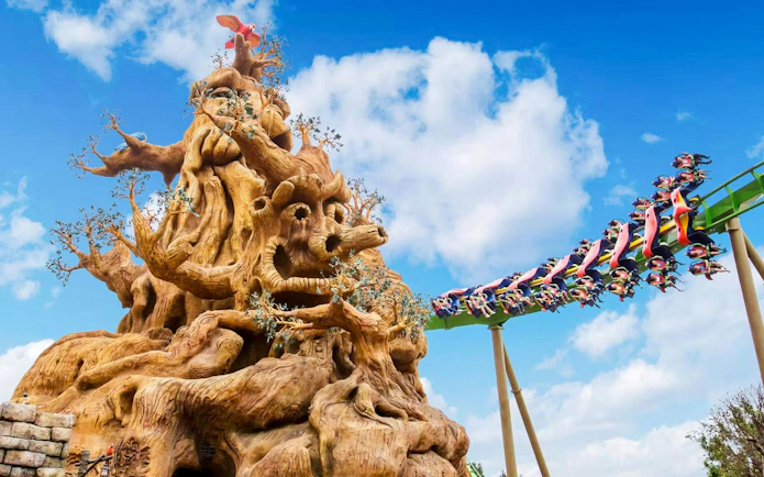Parrot Coaster wing coaster near jungle-themed rockwork at Zhuhai Chimelong Ocean Kingdom, China.