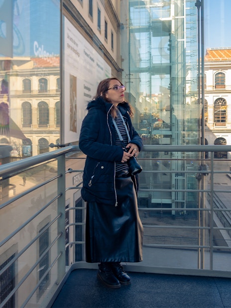 Woman observing art at Reina Sofia Museum, Madrid, with Spanish flag visible outside.