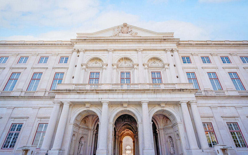 National Palace of Ajuda facade with grand arches and ornate windows in Lisbon, Portugal.