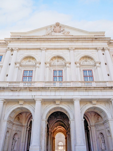 National Palace of Ajuda facade with grand arches and ornate windows in Lisbon, Portugal.