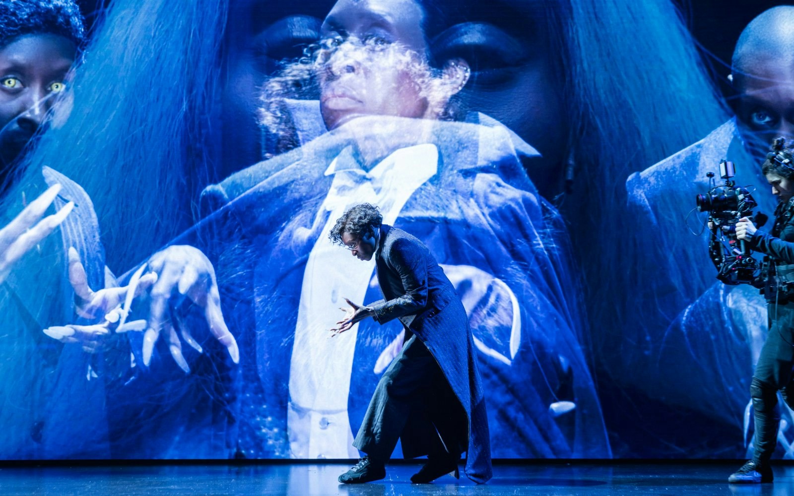 Performer in dramatic pose during Dracula Westend show with eerie blue lighting.
