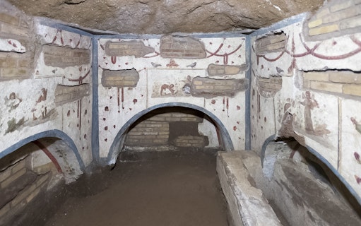 Ancient Roman catacombs with frescoes and arched niches in Rome.