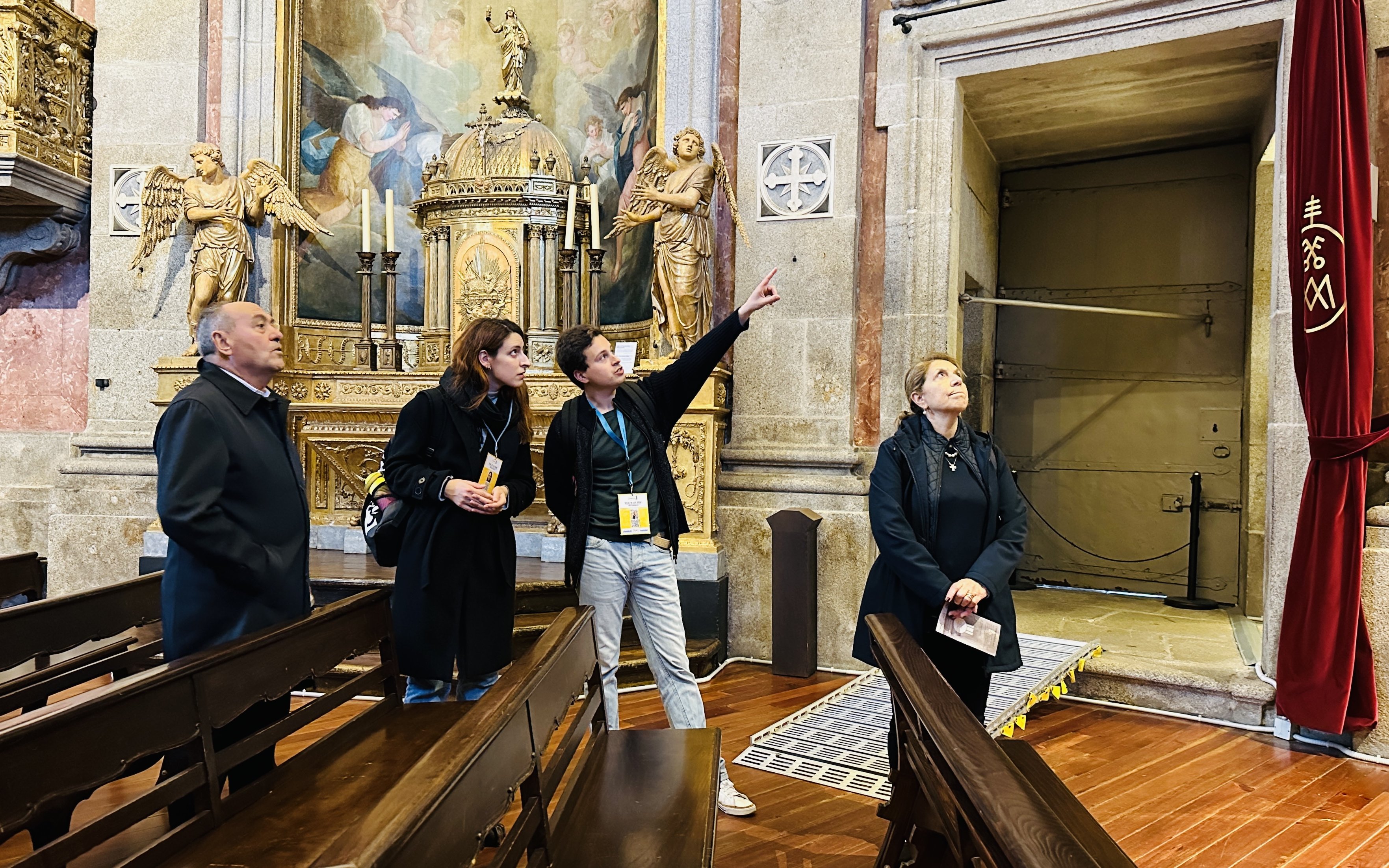 Visitors on a guided tour inside Clérigos Church, Porto, observing ornate altar and artwork.
