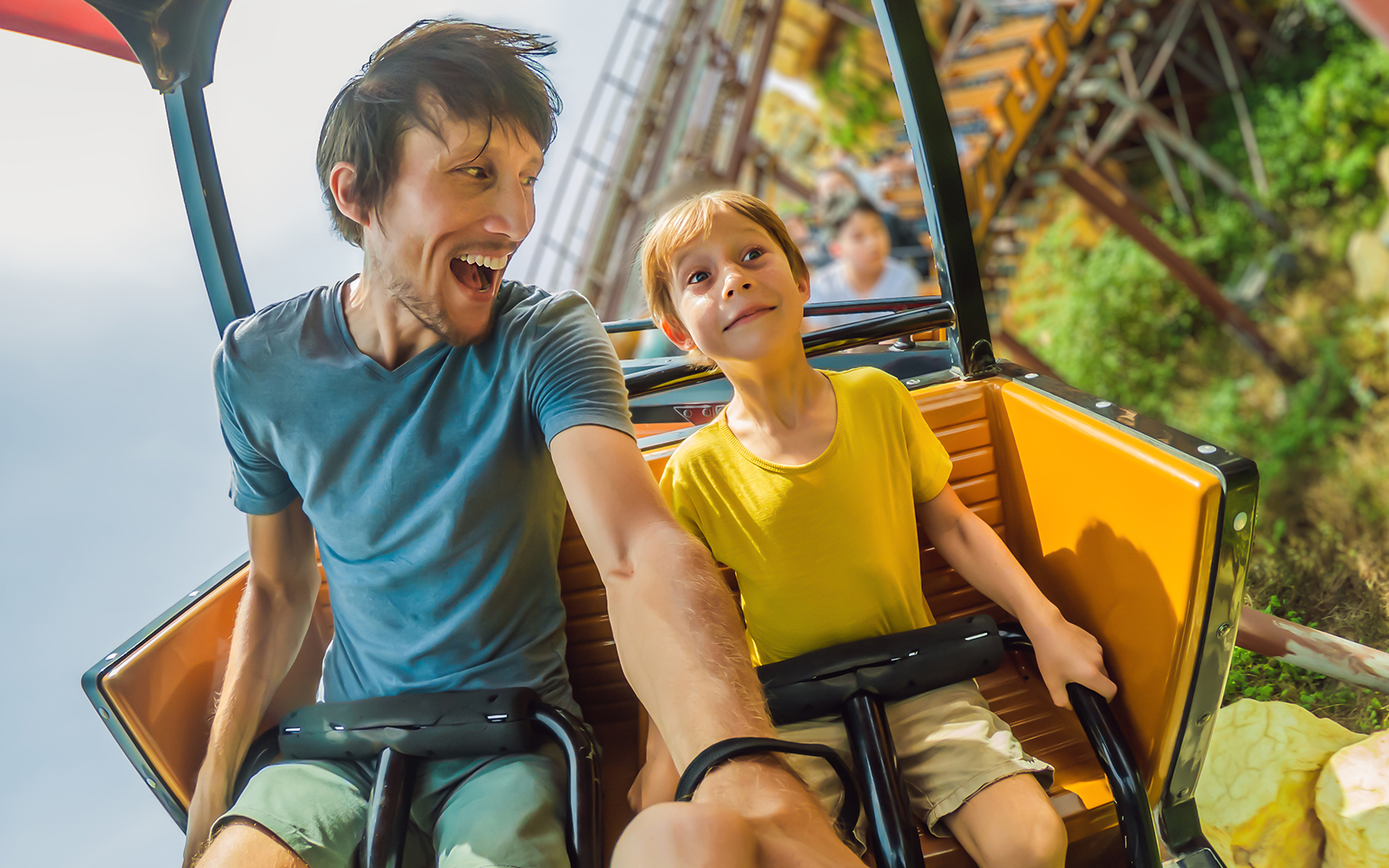 Father and son enjoying a roller coaster ride at an amusement park.