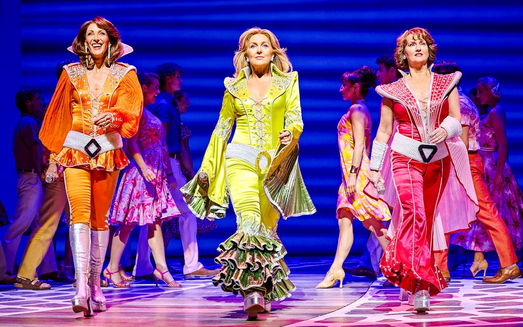 Performers in colorful costumes on stage during a Mamma Mia production.