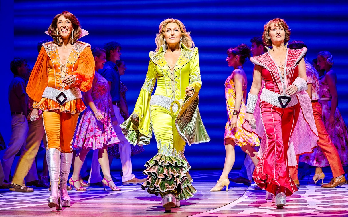 Performers in colorful costumes on stage during a Mamma Mia production.