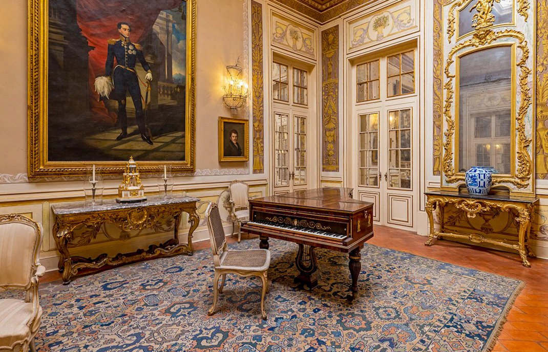 National Palace of Queluz Lantern Room with ornate furniture and large portrait.