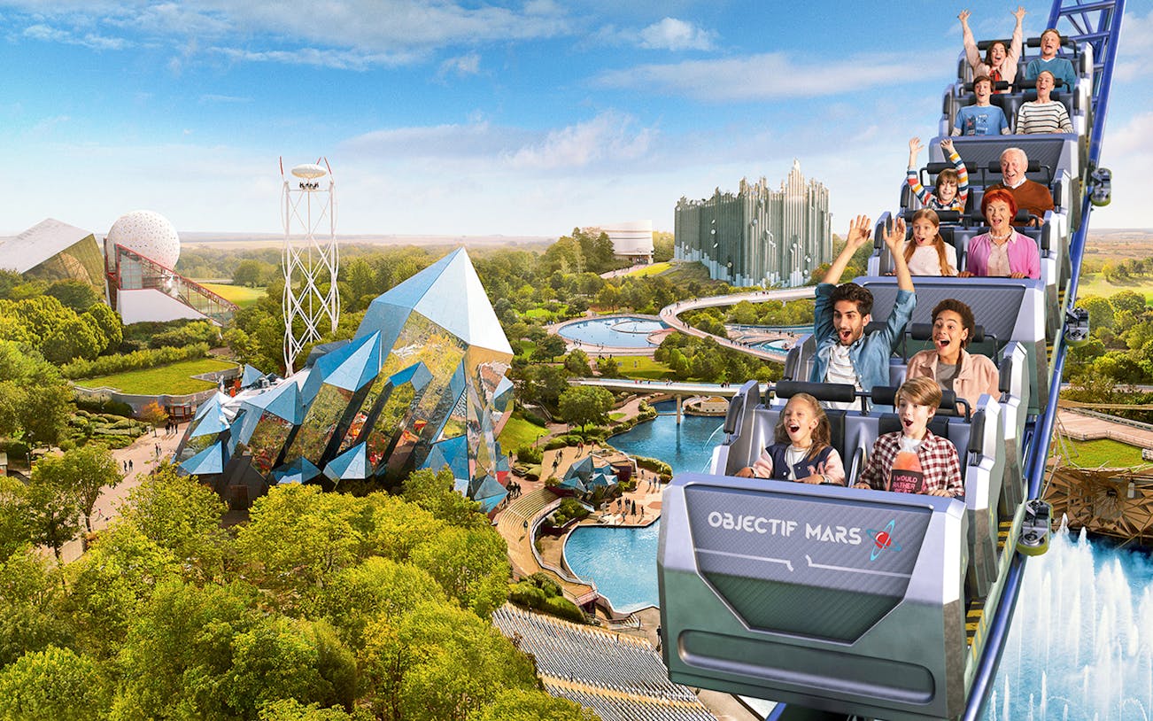 Roller coaster at Futuroscope with excited riders and futuristic architecture in the background.