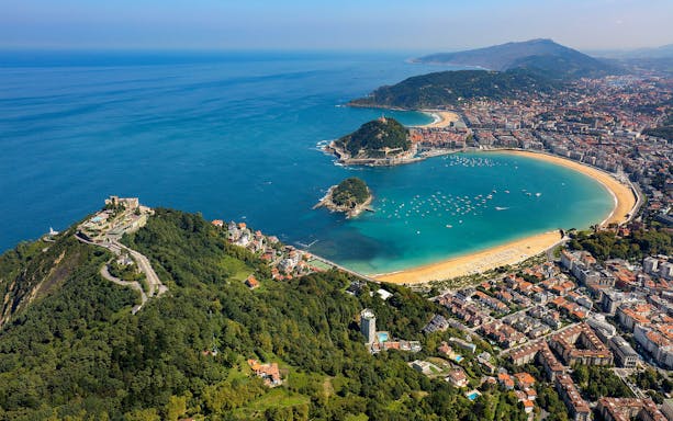 Aerial view of La Concha Bay in San Sebastian, Spain, with surrounding cityscape and coastline.