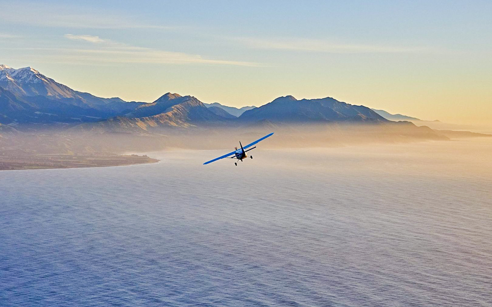 Airplane flying over Kaikoura coast during sunset.