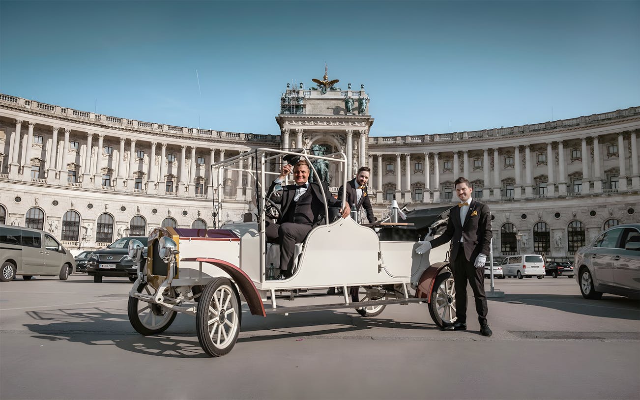 Electro vintage car tour in front of historic building in Vienna.