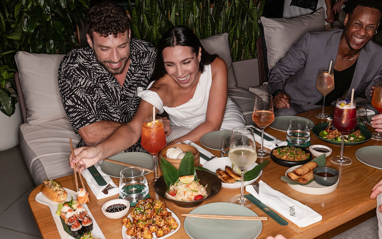 Group enjoying dinner with drinks at Aura Sky Pool restaurant.