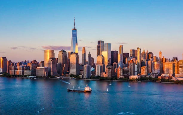 Aerial view of New York City skyline with One World Trade Center at sunset.