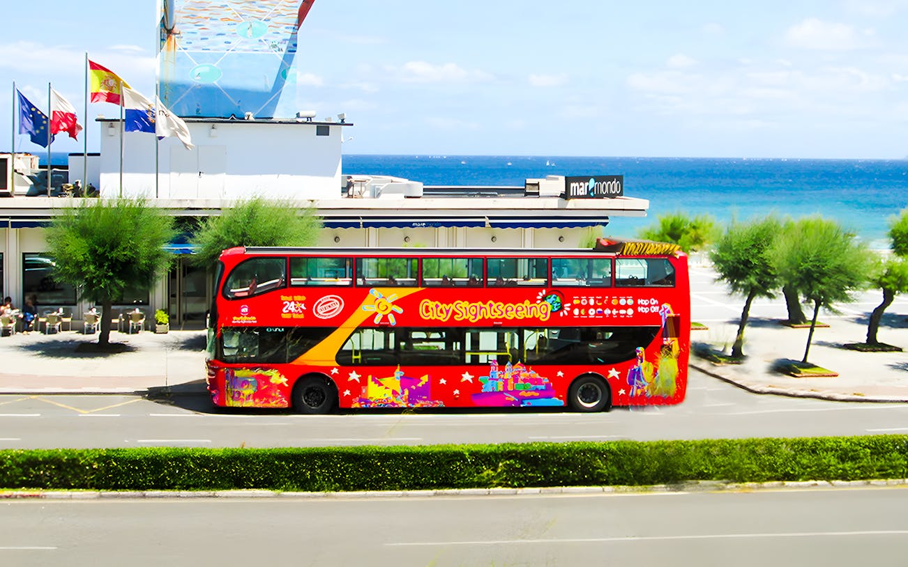 Santander cityscape with red City Sightseeing bus near waterfront and historic buildings.