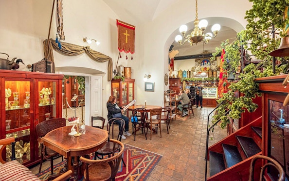 Prague café interior with patrons enjoying drinks, part of historical sightseeing cruise experience.