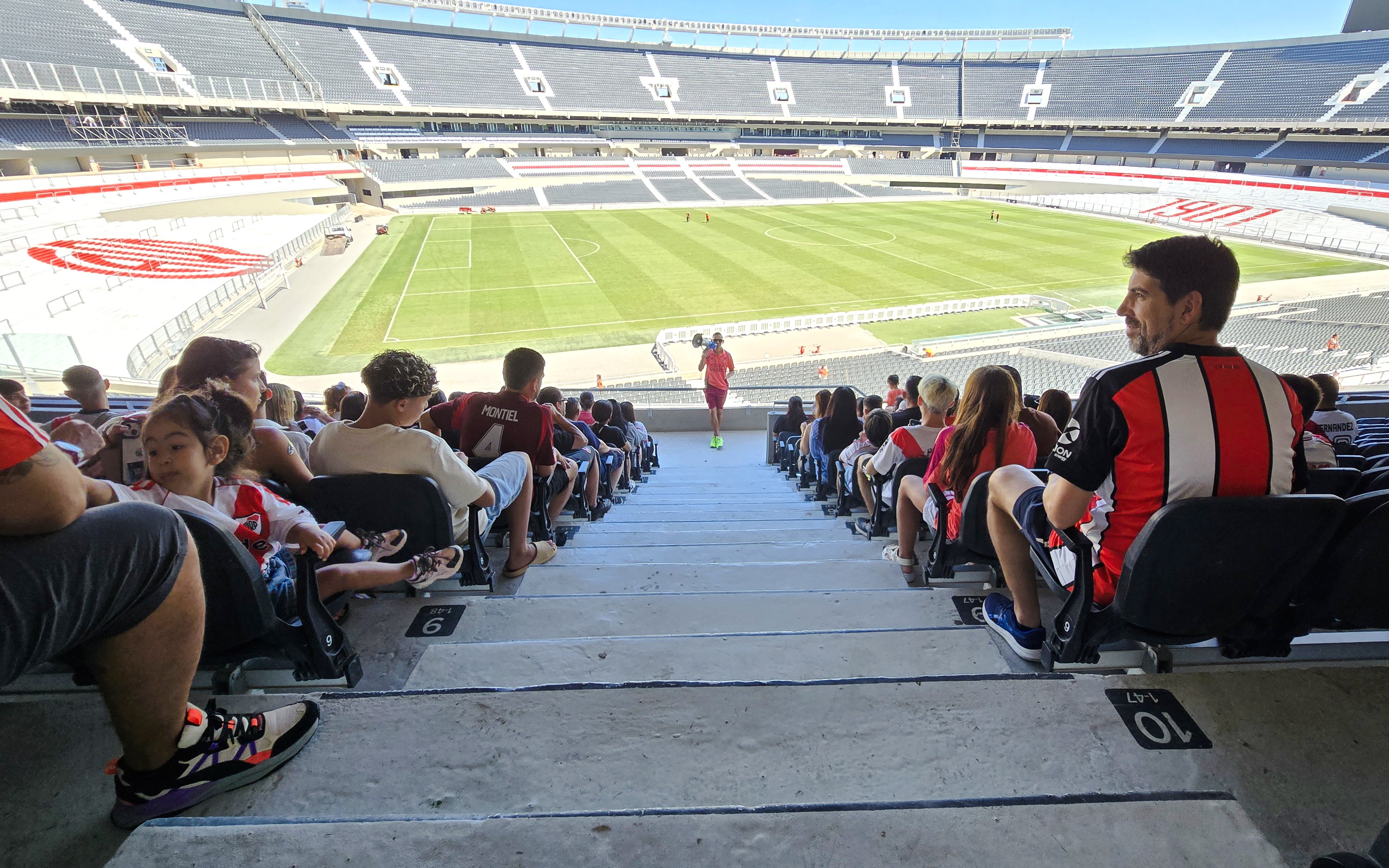 Guests seated at Estadio Monumental, home of River Plate, overlooking the football field.