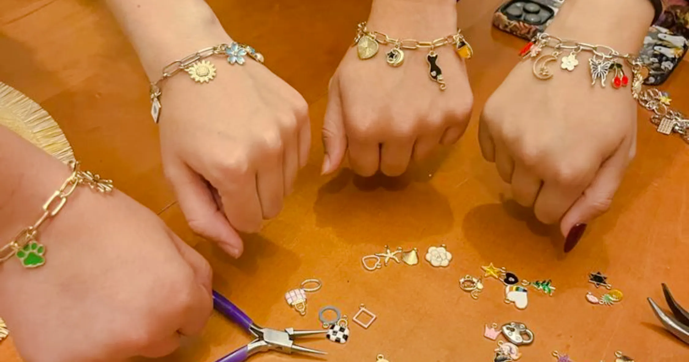 Hands displaying handmade charm bracelets at a jewellery workshop in Essaouira.