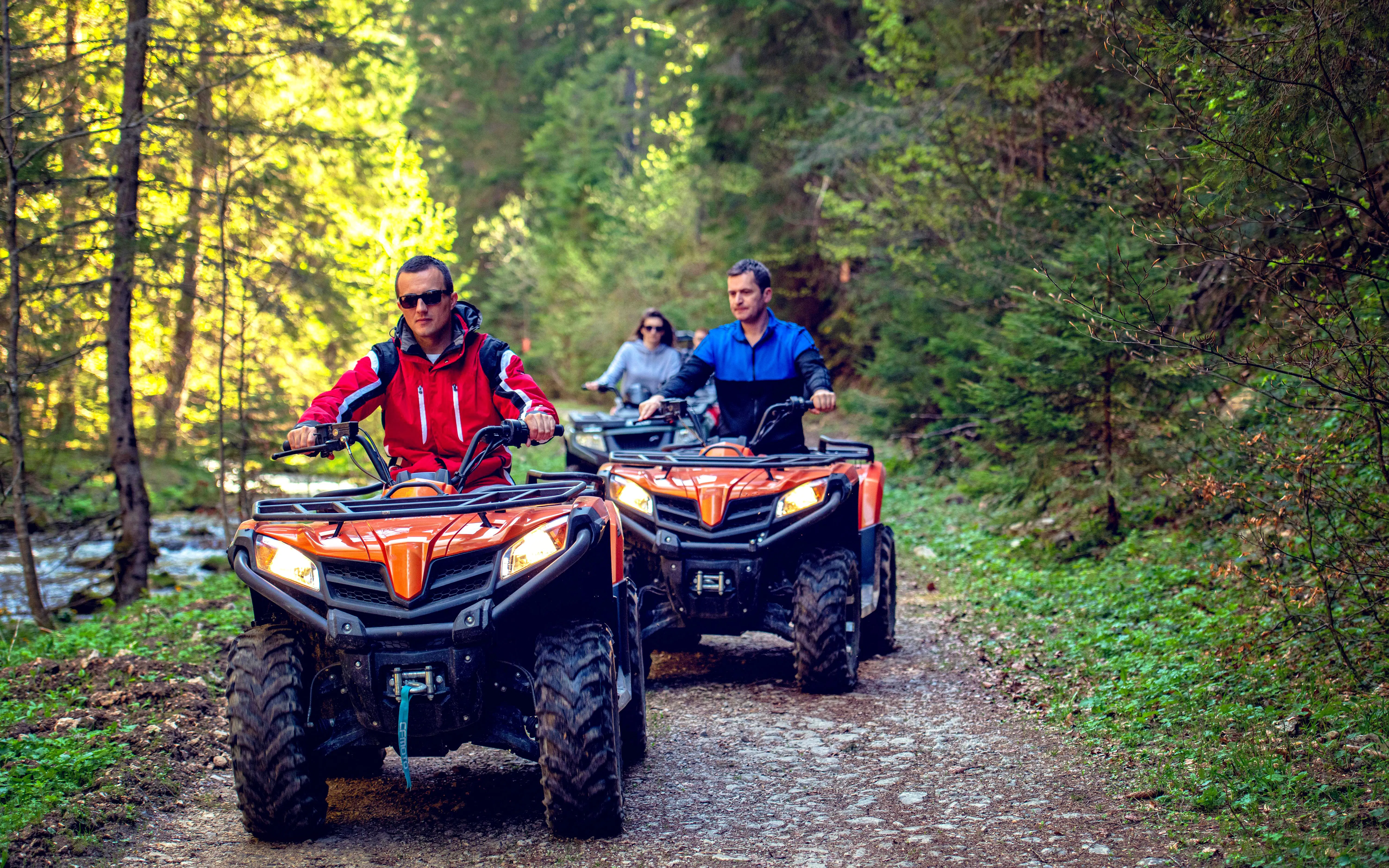 ATV riders on a forest trail adventure.
