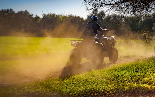Quad bike on a dusty trail in Algarve countryside.