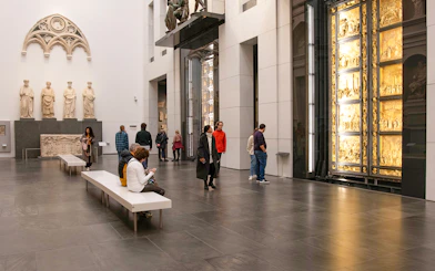 Visitors inside Florence Duomo museum viewing sculptures and the Gates of Paradise.