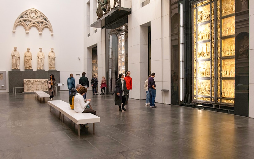 Visitors inside Florence Duomo museum viewing sculptures and the Gates of Paradise.