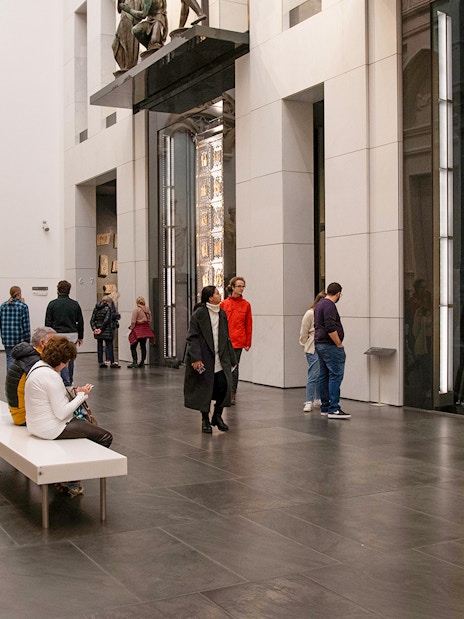Visitors inside Florence Duomo museum viewing sculptures and the Gates of Paradise.