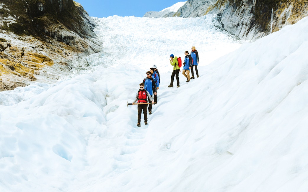 Group hiking on Fox Glacier during guided helicopter tour in New Zealand.