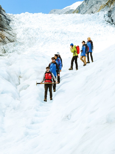 Group hiking on Fox Glacier during guided helicopter tour in New Zealand.