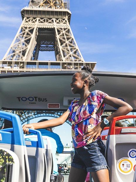 Girl standing on Tootbus upper deck with Eiffel Tower in background, Paris.