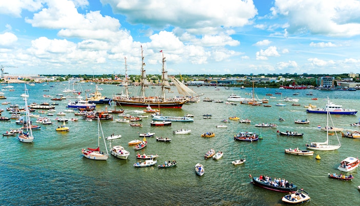 Tall ships and boats in a parade during Sail Amsterdam event.