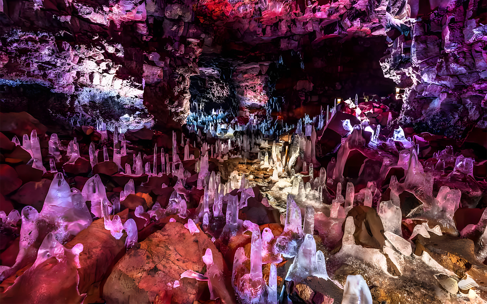 Crystals inside Raufarhólshellir Lava Cave, Iceland, illuminated with colorful lights.