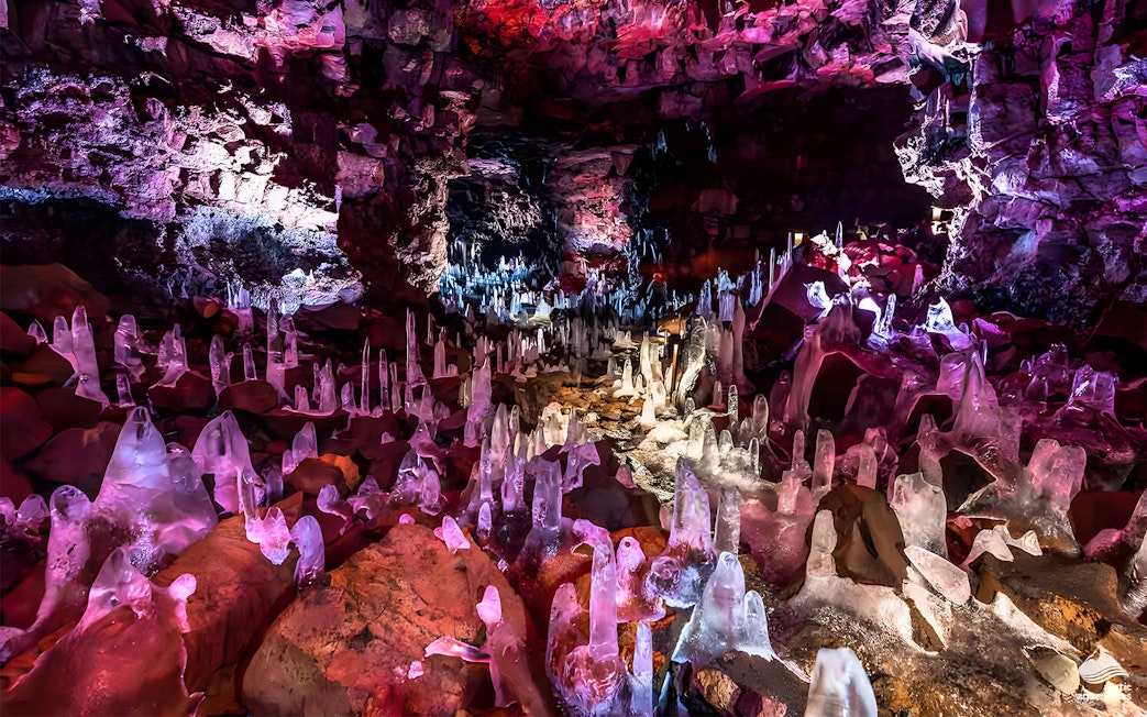 Crystals inside Raufarhólshellir Lava Cave, Iceland, illuminated with colorful lights.