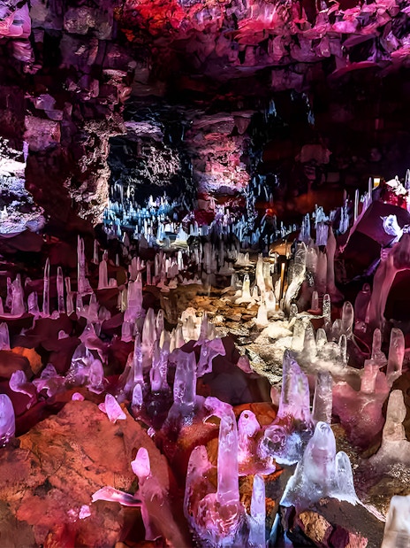 Crystals inside Raufarhólshellir Lava Cave, Iceland, illuminated with colorful lights.
